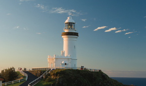a lighthouse on a hill with blue skys in the background