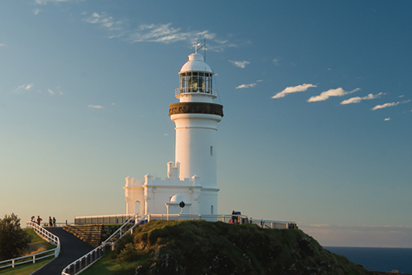 a lighthouse on a hill with blue skys in the background