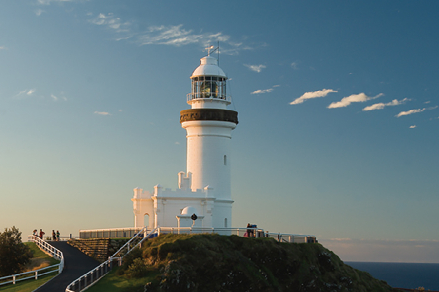 a lighthouse on a hill with blue skys in the background