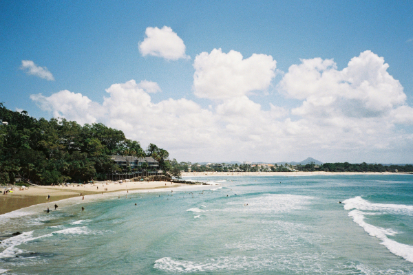 a coastline with a sandy beach and rolling waves in Noosa with JOEY travel