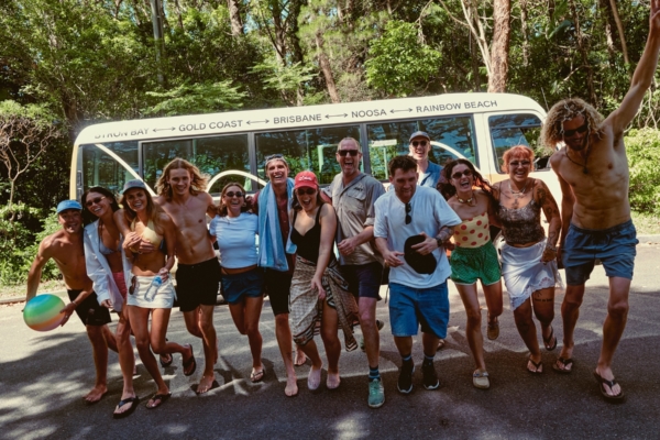 a group of friends running towards the camera infront of a multicoloured joey bs