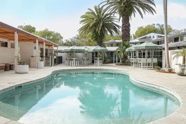 A view of the pool and lounge areas with sun shade and a pool bar in the background