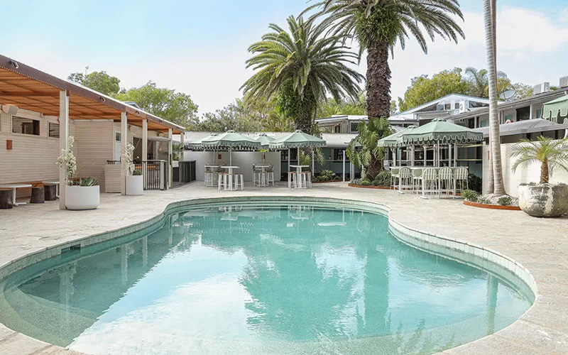 A view of the pool and lounge areas with sun shade and a pool bar in the background