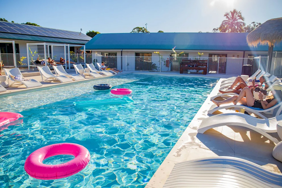 a group of friends relaxing on sunloungers by the pool at Freedom Hostel Rainbow Beach