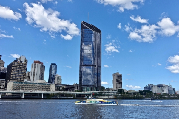A view of the Brisbane river with the skyline in the background and a ferry on the river